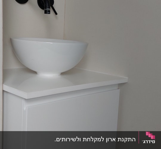 כיור עגול על ארון עץ לבן עם ברז שחור